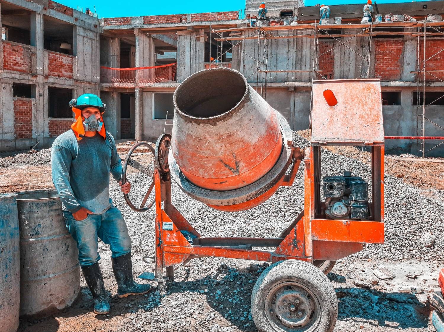 Worker with concrete mixer on site